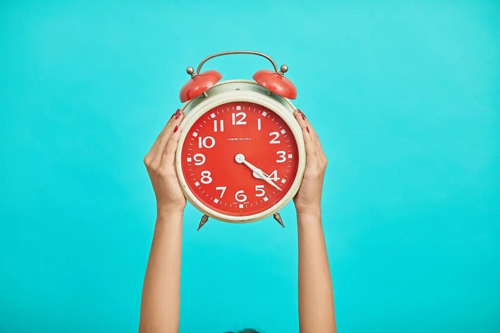 How To Find The Best Last Minute Cruise Deals In 2024 person holding red and beige twin bell analog alarm clock