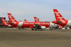 Multiple AirAsia airplanes parked on a tarmac at an airport, showcasing aviation travel.